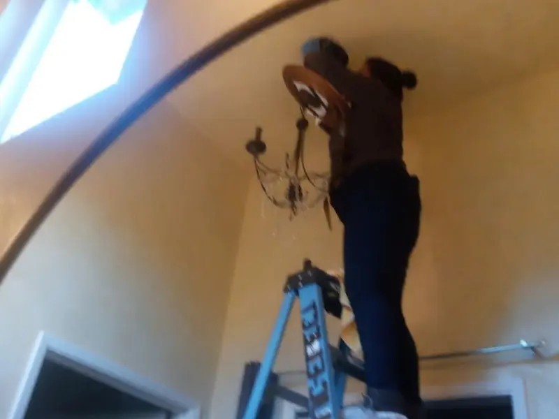 Electrician installing a chandelier in a Silver Firs residence